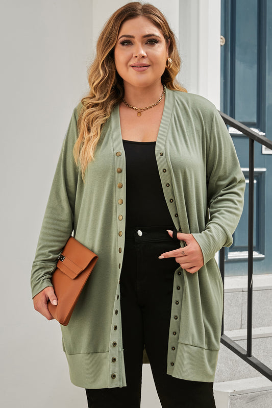 A versatile and dainty addition to any wardrobe, this green plus-size cardigan features a snap-button closure and ribbed trim for a vintage feel. With convenient pockets, it's perfect for adding a touch of warmth while running errands or lounging at home. Pair with a long-sleeve top and skinny pants for a complete casual look. (Fits ladies of all sizes!)