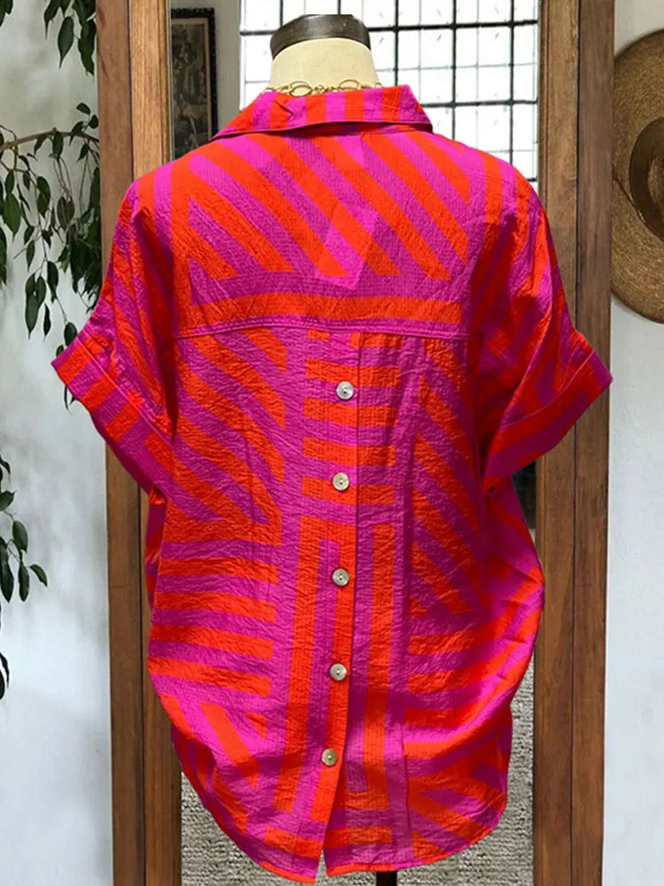 Transform your wardrobe with our Button Down Cotton Blouse! Made from high-quality cotton, this blouse features a trendy turn down collar and short sleeves for a chic look. The vibrant tribal print in bright pink, orange, and purple stripes adds a pop of color to any outfit. With its button down design and unique slit back, this blouse is both stylish and functional. Upgrade your style game today!