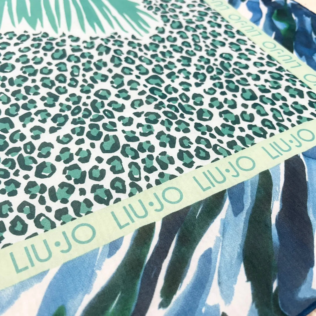 The motif is a large palm tree on a turquoise leopard print rectangle inside blue and green and white abstract stripes. the leopard is bordered in green Liu-Jo