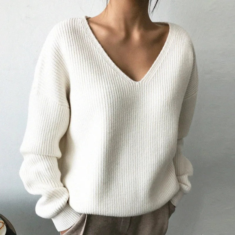 In Natural White - Stay cozy and stylish this fall and winter with our Elegant Solid Color Ribbed V-Neck Sweater. Crafted with an oversized fit and soft knit fabric, this sweater will keep you warm while making a fashion statement. Embrace the season in comfort and elegance.