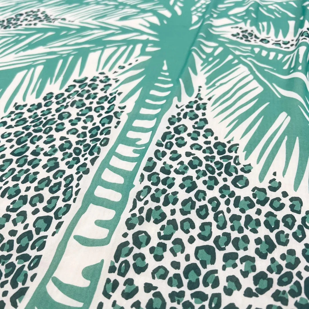 The motif is a large palm tree on a turquoise leopard print rectangle inside blue and green and white abstract stripes. the leopard is bordered in green Liu-Jo