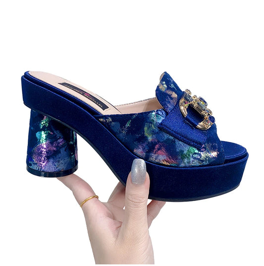 The platform of the shoe is a rich blue, the heel is round with a shiny metallic abstract design.  The same print is on the foot strap of the sandal.  there is a solid color strap across the top with a D ring diamond design.