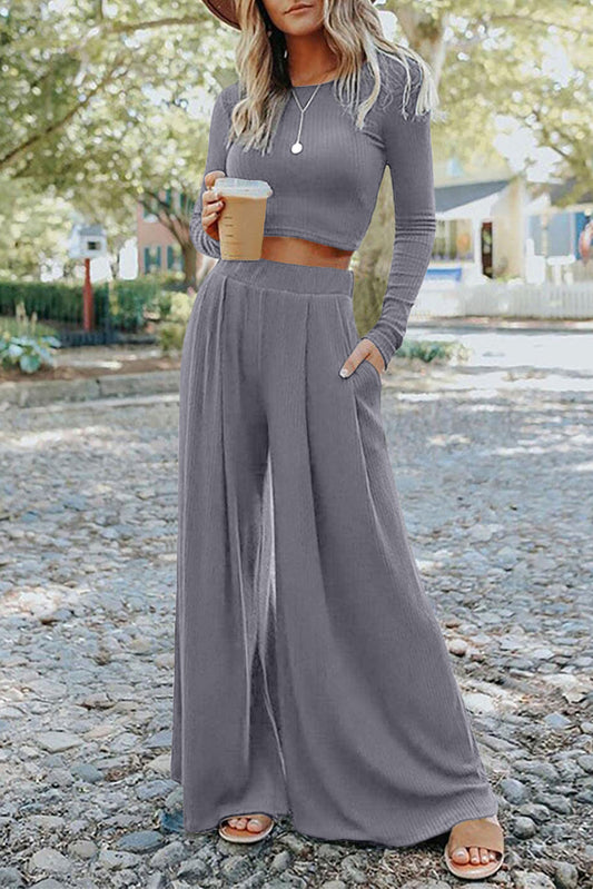 Effortlessly chic and versatile, the Gray Solid Color Ribbed Crop Top Long Pants Set is perfect for both casual and dressy occasions. Mix and match for endless styling options, while the high waist and wide leg design flatters and elongates your figure. The crop top adds a stylish touch, making this set a must-have in your wardrobe!