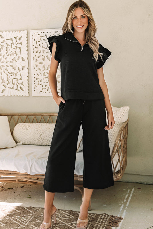 Stand out in style with our Black Textured Flutter Sleeve Top Wide Leg Pants Set. The top features flutter sleeves for a feminine touch, while the wide leg pants offer both comfort and a flattering silhouette. Elevate your wardrobe with this chic and versatile set.